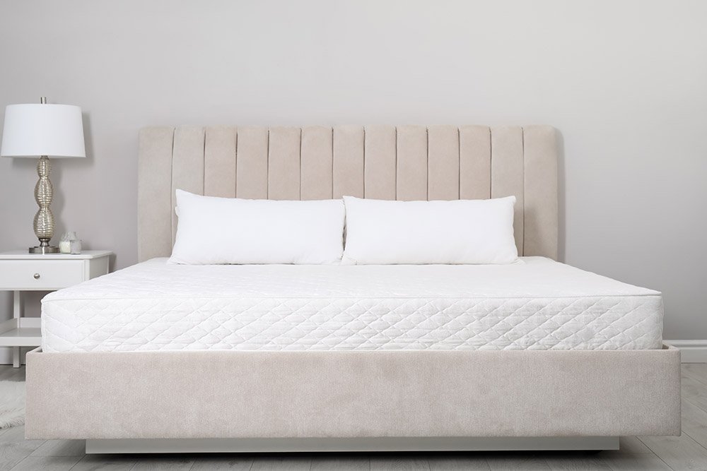 Comfortable bed with soft white mattress and pillows indoors